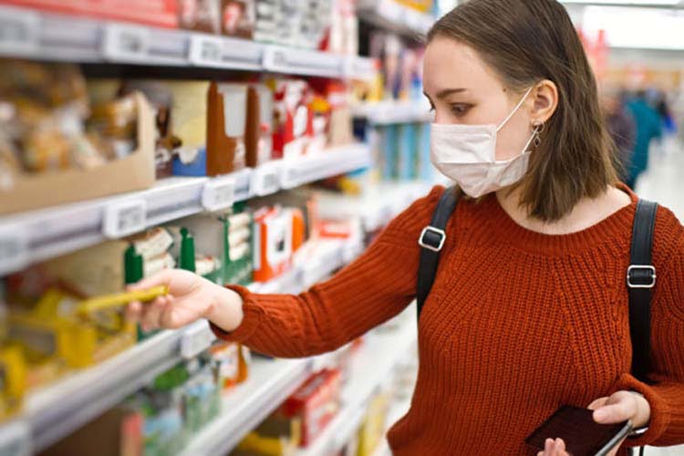 Durante períodos especiales, una mujer con máscara compra la comida empaquetada.